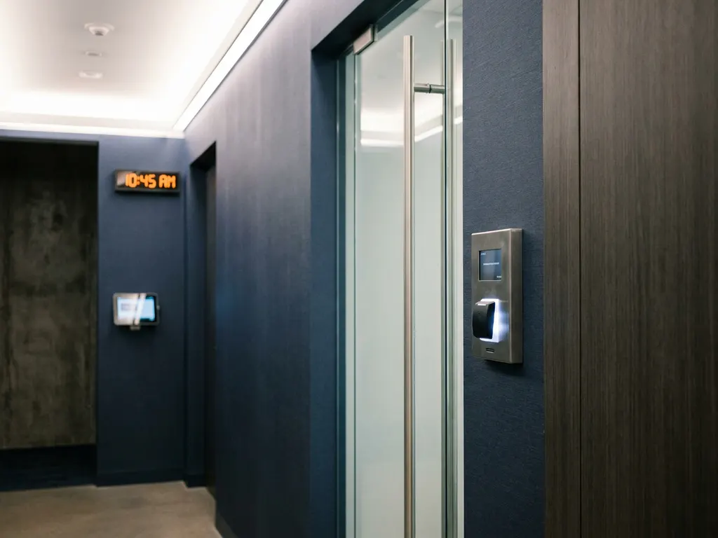 Elektronisches Zutrittspanel mit Kartenleser neben Glastür, digitale Zeiterfassungsterminal im modernen Büroflur.